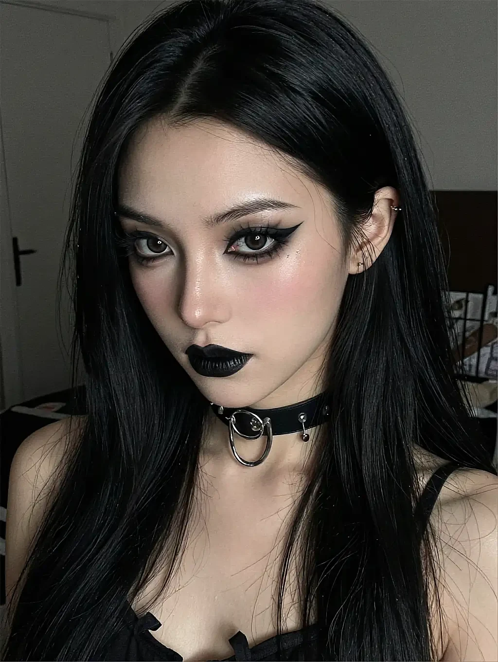 Fictional AI character with black hair, dark eye make-up and a studded choker in a pale room